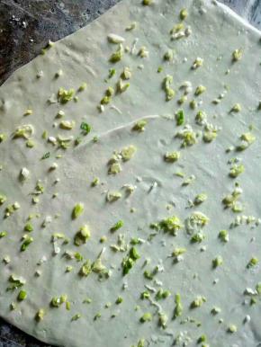 在擀开的面片上均匀的抹上油，撒上少许盐，然后撒上切好的葱花