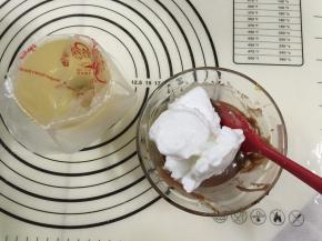 12. 将三分之一的蛋白霜倒入可可蛋黄糊中，（如果蛋黄糊是4勺的量，那么蛋白霜就加4—6勺，蛋白霜别太多才不会太稀）用手动打蛋器从底部向上拌起，拌至顺滑细腻的程度，事先准备好裱花袋用一个杯子把袋子装好，以免倒蛋黄糊时手忙脚乱的