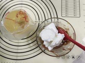 12. 将三分之一的蛋白霜倒入可可蛋黄糊中，（如果蛋黄糊是4勺的量，那么蛋白霜就加4—6勺，蛋白霜别太多才不会太稀）用手动打蛋器从底部向上拌起，拌至顺滑细腻的程度，事先准备好裱花袋用一个杯子把袋子装好，以免倒蛋黄糊时手忙脚乱的