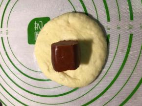 用手掌按扁排除气泡，放入一颗火腿肠，包好收口。