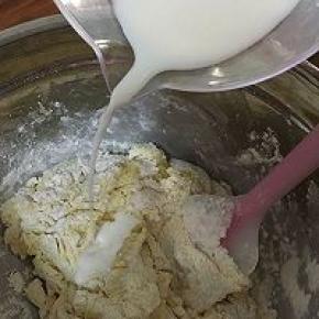随后，倒入一半的牛奶，使用拌刀翻拌。按照干粉——牛奶——干粉的步骤，将干粉和牛奶拌入盆中，不要过度搅拌，直到没有干粉即可。