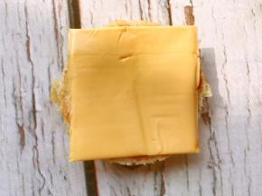 汉堡底部抹上番茄酱放上一片芝士片。