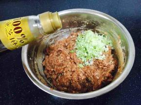 最后放入葱花，在葱花上放约20g左右的香油，先用香油把葱花拌匀，再将葱花与肉馅充分调匀，即朝一个方向搅拌均匀，大约搅拌100下左右。
先用油裹住葱花的目的是防止葱汁外溢，造成肉馅葱味过重。