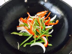 锅里放少许玉米油，先炒洋葱，当洋葱炒出香味，放入青红椒丝，翻炒几下断生即可盛出备用。