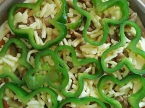 抹上披萨酱，撒上一层奶酪，铺上鸡丁肉，再撒上一层奶酪，上面铺上青椒圈

