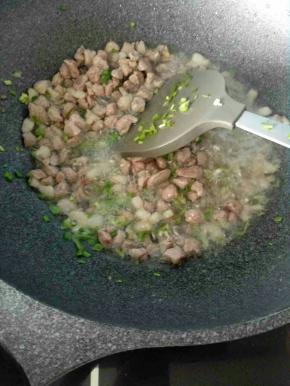 5、倒入瘦肉丁翻炒，中途加入葱姜一起炒。