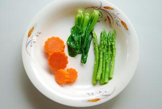 将胡萝卜用模具切成形状，然后，依次将胡萝卜、小菜芯、芦笋过水煮熟