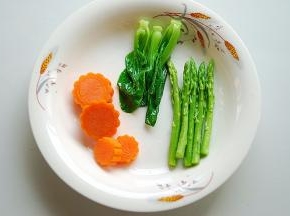 将胡萝卜用模具切成形状，然后，依次将胡萝卜、小菜芯、芦笋过水煮熟