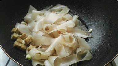 炒锅烧热，倒花生油，放葱花、蒜翻炒下，放入面筋、凉皮。