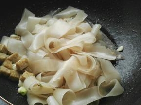 炒锅烧热，倒花生油，放葱花、蒜翻炒下，放入面筋、凉皮。