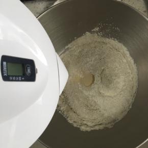 混合均匀的面粉中间挖一个小坑，小坑内倒入活性干酵母，慢慢加入水