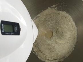 混合均匀的面粉中间挖一个小坑，小坑内倒入活性干酵母，慢慢加入水