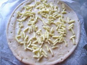 披萨饼坯上撒上马苏里拉奶酪；