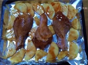 烤盘铺上锡纸，将鸡腿放入烤盘内，周围码放上土豆片；