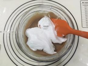 15. 再挖1/2的蛋白霜进蛋黄糊中，用刮刀从盆底由下向上快速翻拌