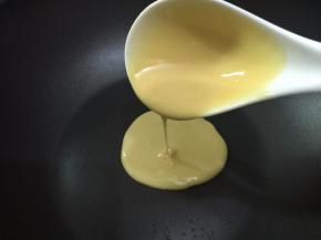 用大勺子舀起一勺面糊，倒面糊时，勺子始终不能移动定在一个点上面糊会自然摊开，成为一个圆形