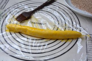 将变硬的面团取出，放在保鲜膜上，刷一层蛋黄液