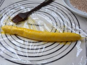 将变硬的面团取出，放在保鲜膜上，刷一层蛋黄液