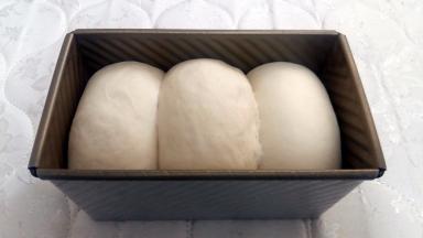 放入吐司模，盖保鲜膜，发酵至八分满，盖上盖子。