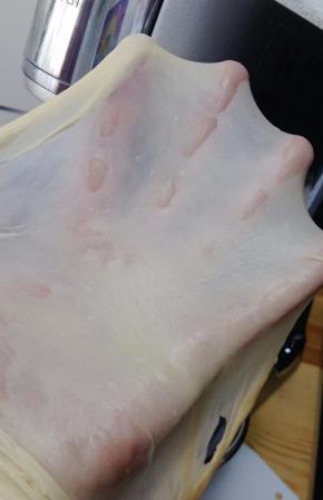 除黄油外的所有材料倒入厨师机，面团揉至光滑，能抻出半透明的薄膜，抻开的洞口呈锯齿状，加入软化的黄油。继续揉至能抻出透明结实的薄膜，也就是做吐司要求的完全阶段。