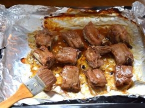 将烤盘端出，表面的锡纸去掉，用刷子蘸腌排骨的汁刷在排骨表面；