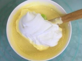 取三分之一的蛋白霜到蛋黄糊里，用刮刀翻拌均匀。