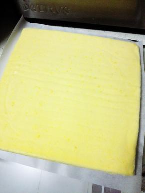 待蛋糕体至温热，取一张新的油纸还在蛋糕体上，然后迅速翻面，撕掉原来的油纸，切掉上下两端蛋糕（少许）