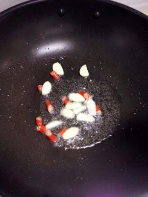 炒锅倒入适量的油， 下入切好的红辣椒和大蒜片煸炒出香。