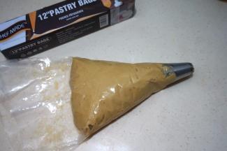 大号曲奇花嘴入裱花袋中，将面糊刮入袋中；此时烤箱开始预热170度，上下火