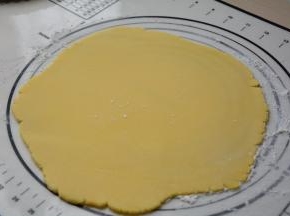 冷藏变硬的面团取出来，在揉面垫上撒少许面粉，在面团上也撒少许面粉，擀成厚约3毫米的面片，厚度也随派盘大小来调整