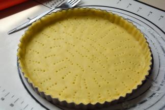 用擀面杖将面皮卷起，移到派盘上，用手掌轻轻将派皮按压进派盘中，将多余的派皮贴补到薄或者少的地方，将全部的材料都用完；再用餐叉在上面均匀扎孔，防止烘烤时不平；此时烤箱开始预热180度