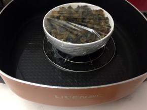 将切碎的梅菜放入碗中，然后在碗口封上保鲜膜
