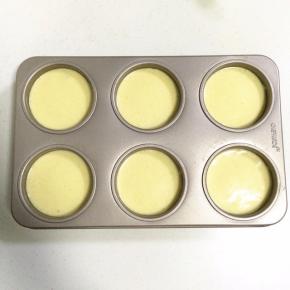 翻拌好的蛋糕糊倒入模具中指示线的位置，震动几下，震出气泡。