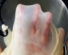 除黄油和黑芝麻外的所有材料倒入厨师机，面团揉至光滑，能抻出半透明的薄膜，抻开的洞口呈锯齿状，加入软化的黄油。继续揉至能抻出透明结实的薄膜，也就是做吐司要求的完全阶段。