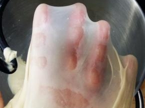 除黄油和黑芝麻外的所有材料倒入厨师机，面团揉至光滑，能抻出半透明的薄膜，抻开的洞口呈锯齿状，加入软化的黄油。继续揉至能抻出透明结实的薄膜，也就是做吐司要求的完全阶段。