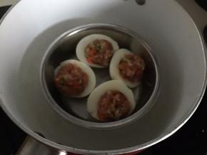 然后蒸好的鸡蛋去壳切成两半，挖去蛋黄，勺入肉末，放入锅中蒸熟即可