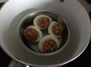 然后蒸好的鸡蛋去壳切成两半，挖去蛋黄，勺入肉末，放入锅中蒸熟即可