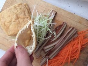 油豆腐一端的边缘切去，胡萝卜、鸡蛋干、蒜抽丝