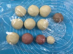 10. 把面团分成7份，7份32克其中1份加入可可粉揉均匀，剩余的分割成平等的2份，一份加红曲粉揉均匀，再分割出原味和加了红曲粉的面团各35克