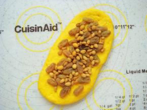 取一份擀成长条状。铺上提前泡软的葡萄干，再撒点瓜子仁。