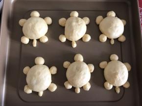 用同样的方法包好6个，将头和脚摆在适当的位置，剩下的6个小面团搓成长条做尾巴，摆在适当的位置。