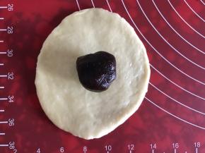 取一个面团，擀成中间厚周围薄的面片，包上豆沙，封口捏紧，揉圆。