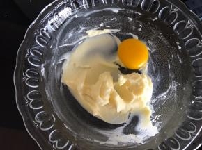 翻拌均匀的黄油加入一个蛋黄，开动电动打蛋器低速打发。
