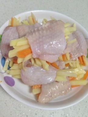 将切好的胡萝卜、土豆丝塞进腌好的鸡翅里面。