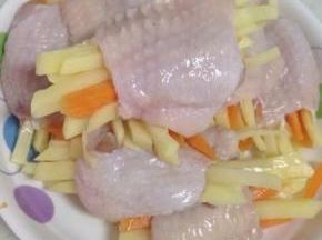将切好的胡萝卜、土豆丝塞进腌好的鸡翅里面。