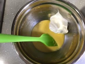 将小部分蛋白霜加入蛋黄糊，用翻拌的手法翻拌均匀。