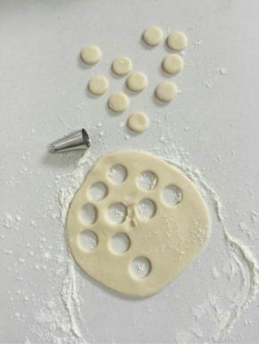 取一个白色小剂子揉圆后，撒少许面粉，用手按扁，再用裱花嘴按压出10个小圆，其中5个用来做猪猪包的鼻子，5个用来制作猪猪包的耳朵！（红色的面团也用同样的办法。）

