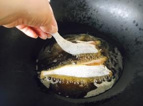 锅里放适量的油，油5、6成热时拎着鱼尾轻轻的贴着油面放到锅里。