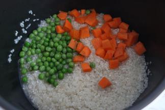 大米淘洗干净后，加入胡萝卜丁、豌豆。