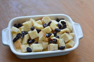 撒一层葡萄干，铺一层吐司块，将剩下的牛奶鸡蛋液倒入烤碗中，表面零星撒几个葡萄干